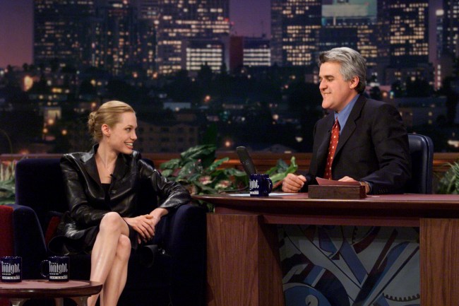 Angelina Jolie wearing black leather and her blonde hair in a bun during an interview with host Jay Leno