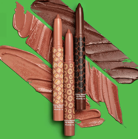 Three tubes of Hard Candy x Girl Scouts Cookie Glaze Lip Marker laid over three brown swatches