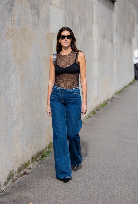 Deborah Reyner Sebag wears denim jeans, black transparent top, silver bag outside Givenchy during the Womenswear Spring/Summer 2024 as part of  Paris Fashion Week on September 28, 2023 in Paris, France.