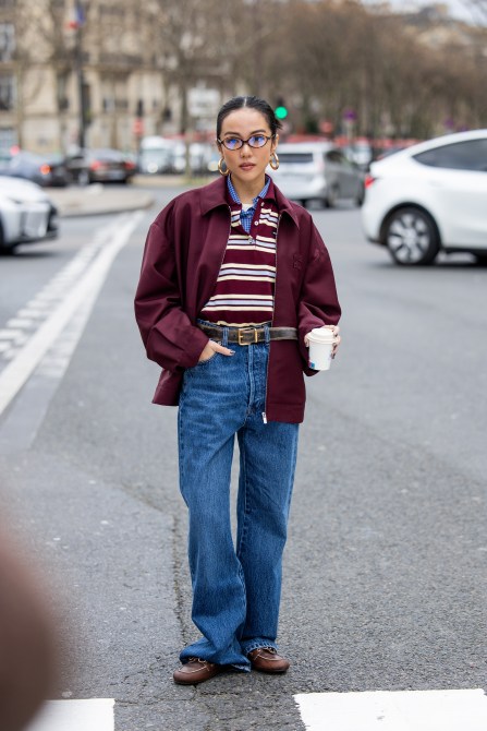 Yoyo Cao wears burgundy jacket, striped polo, denim jeans, glasses outside Miu Miu during the Womenswear Fall/Winter 2024/2025 as part of  Paris Fashion Week on March 05, 2024 in Paris, France.