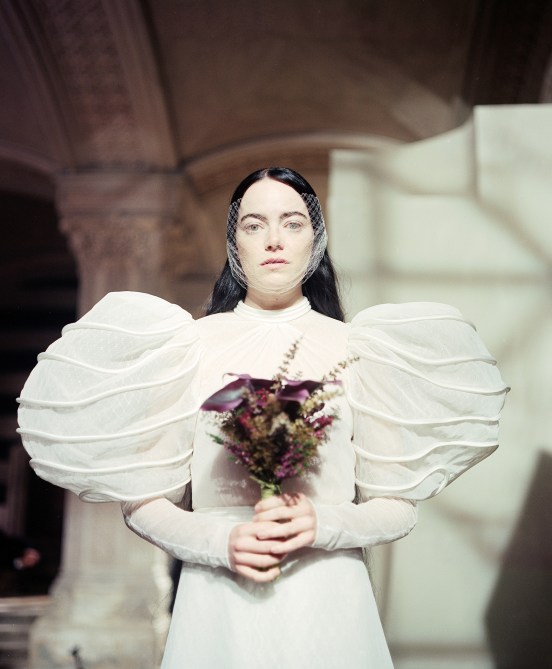 Emma Stone as Bella Baxter in a wedding gown and with a veil over her face.