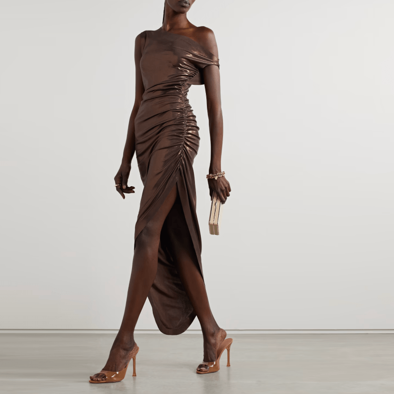 A model wearing a metallic gold-brown dress with an off-the-shoulder neckline and ruched detailing