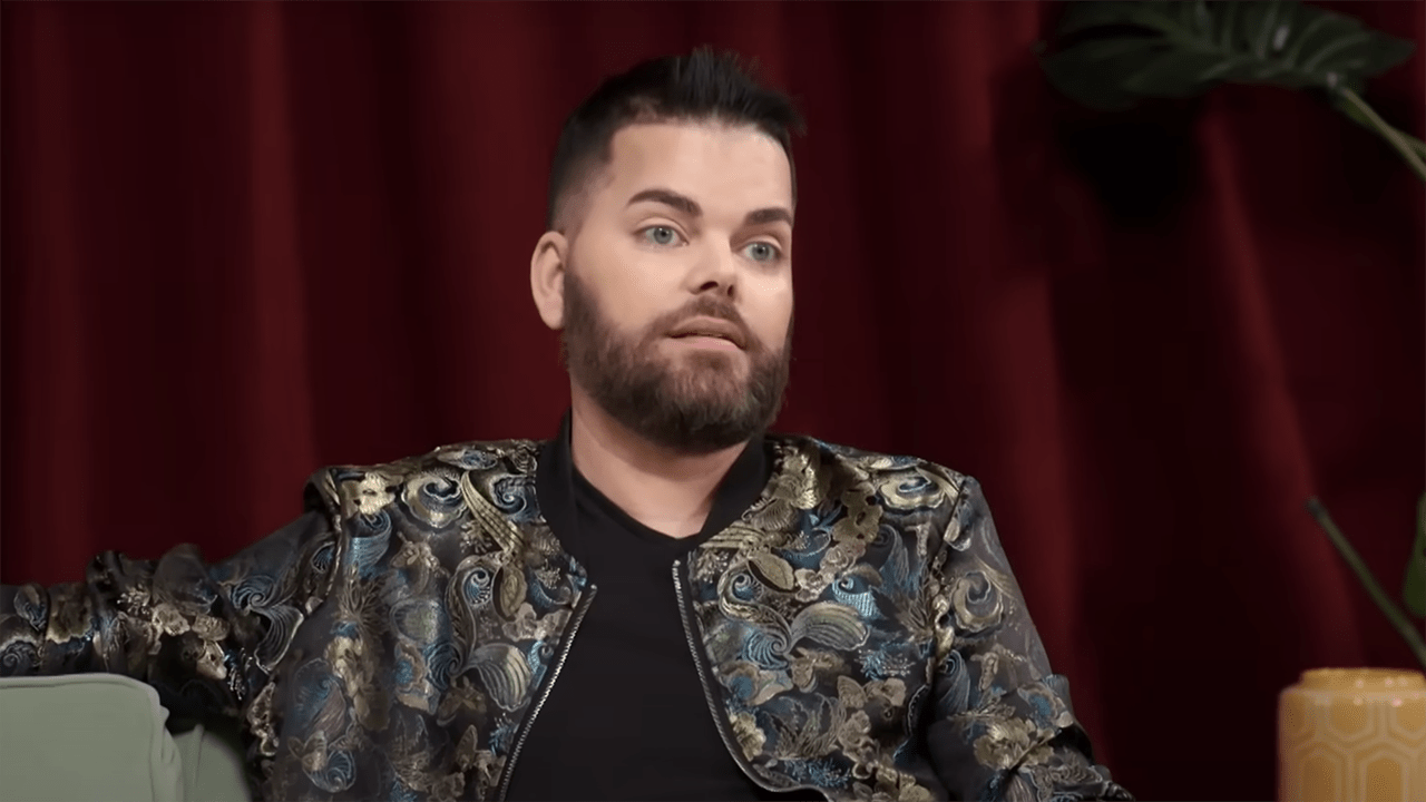 Tim, a white man with black hair and beard in a patterned jacket.