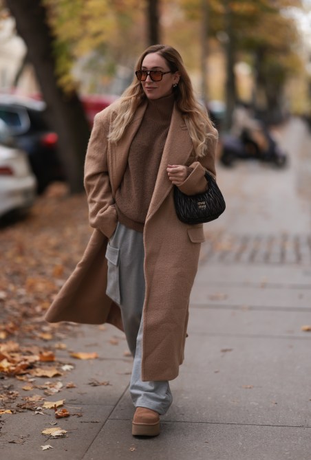 Sonia Lyson seen wearing a brown wool coat and gray sweatpants pants, a beige knit turtleneck sweater, brown Ugg platform boots on November 10, 2022 in Berlin.