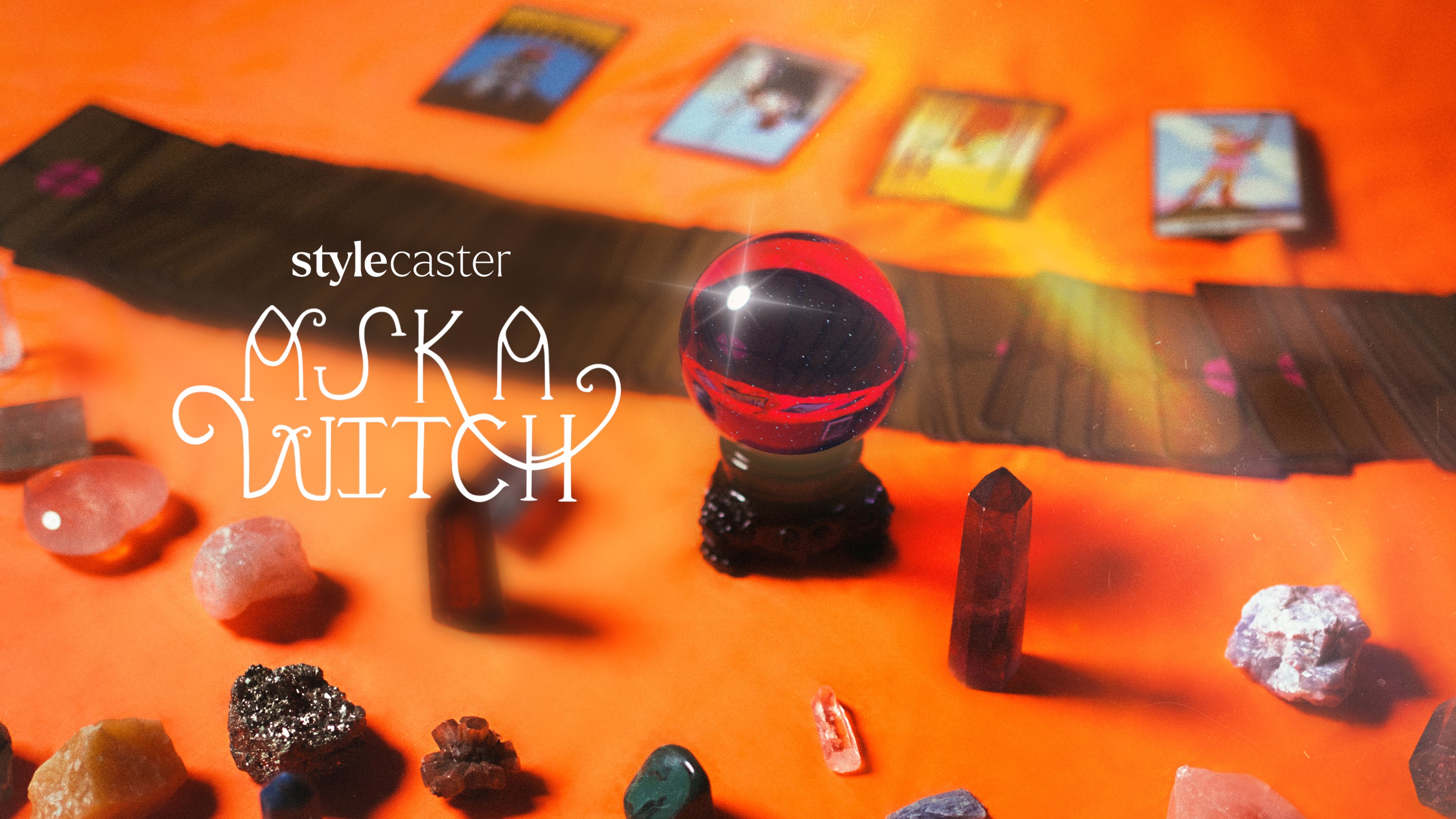 A purple and sparkling crystal ball surrounded by tarot cards and other assorted crystals