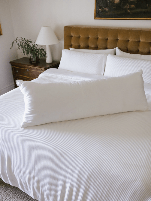 A body pillow placed on a bed with white sheets