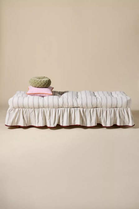 A striped daybed with a ruffle skirt