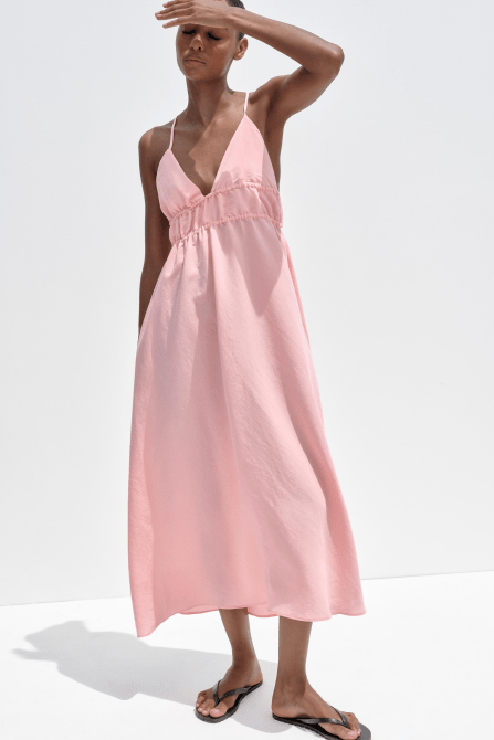A model wearing the Zara Flowy Midi Dress in light pink